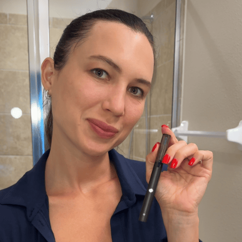 Person holding a black pen in a bathroom.